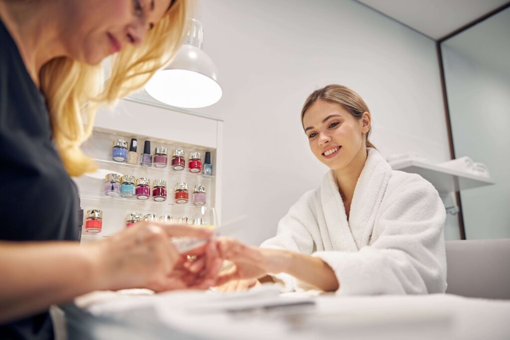 7 high-paying jobs in the beauty industry and how to find them low angle joyful young female sitting table while artist is polishing her nails with file min 1024x683 - 7 high-paying jobs in the beauty industry and how to find them