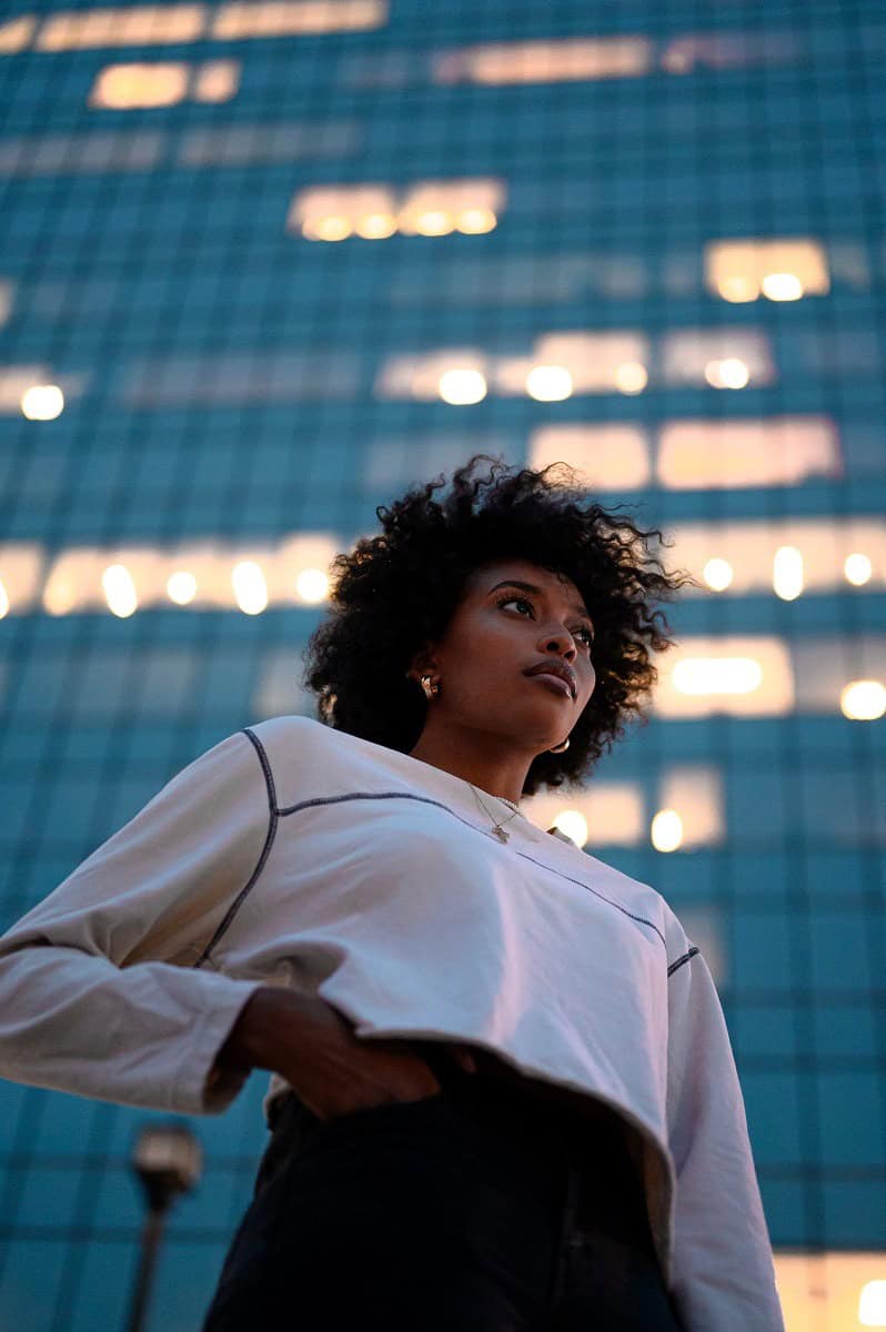 How to prepare yourself for a relationship: confident young woman in front of a glass tower at dusk