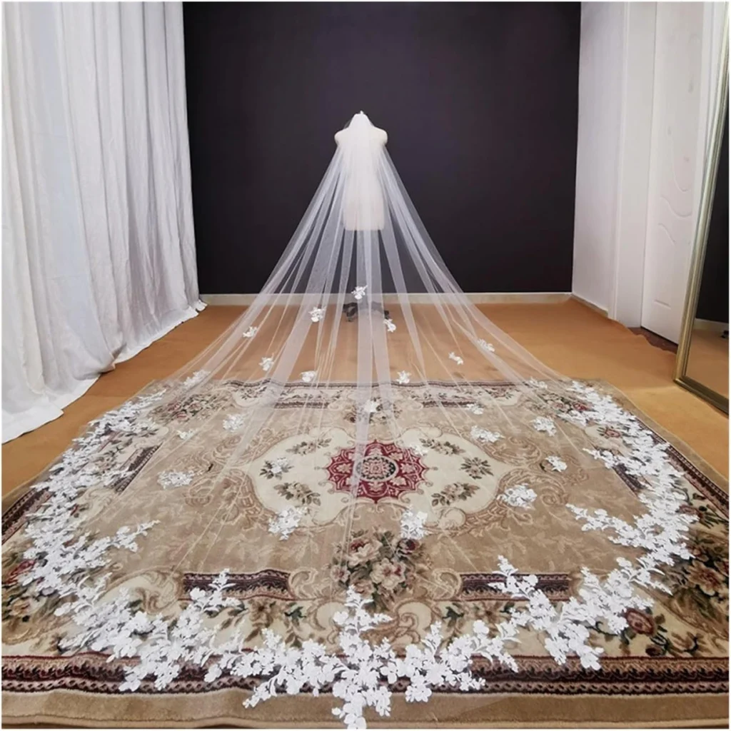 A long wedding veil with intricate ivory ribbon embroidery, creating a soft, elegant look as it gracefully cascades from the bride’s head, perfect for adding a delicate touch to a classic bridal ensemble.