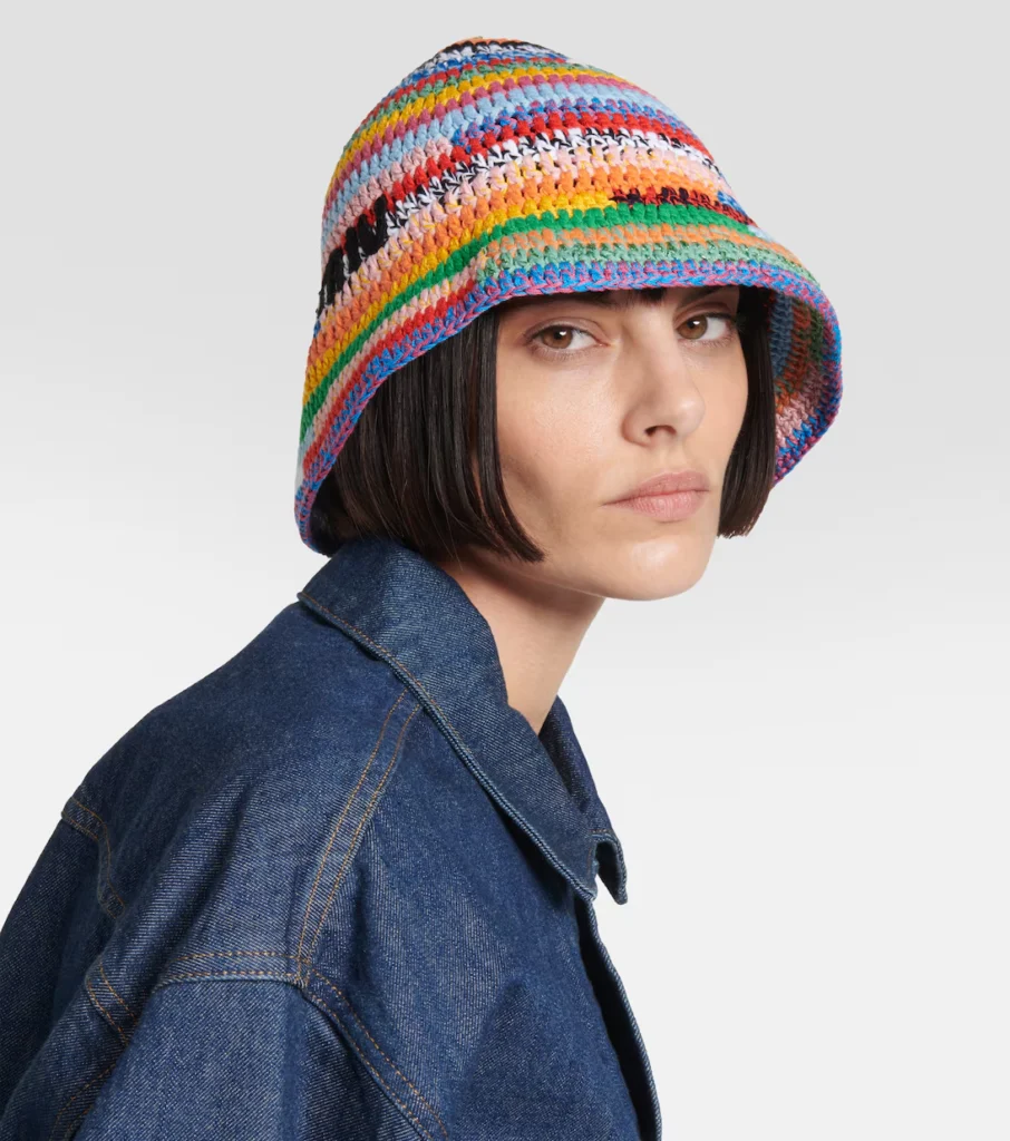 The crochet bucket hat showcases a woven, textured design, providing a comfortable and fashionable accessory that adds a bohemian touch to any summer outfit.