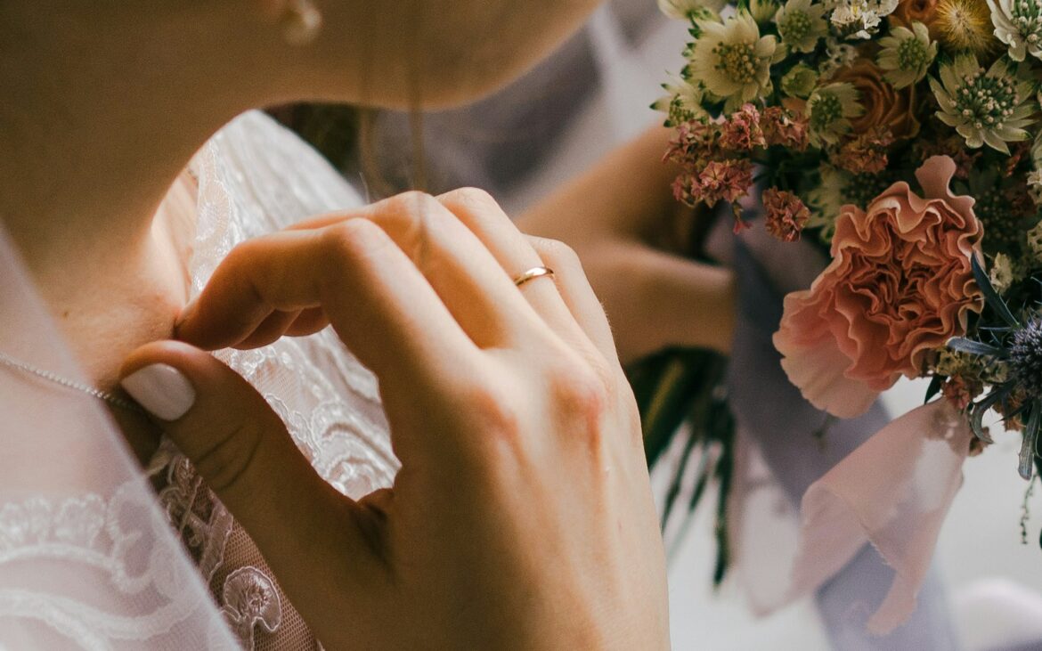 Bride adjusting her gown beside a bouquet while getting ready