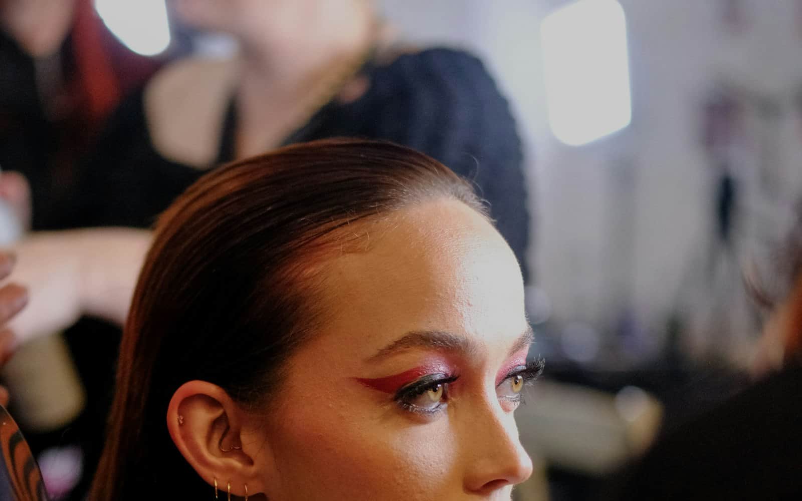 Makeup artist touching up a model backstage before a show