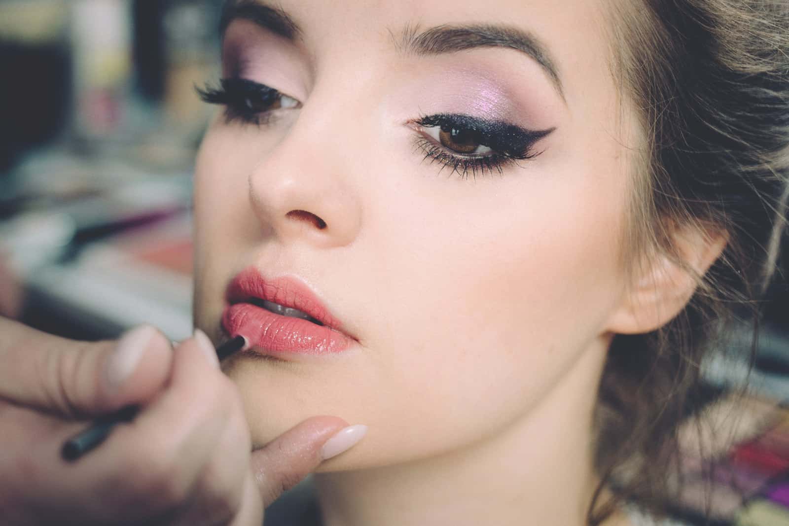 Makeup artist applying lip color to a model with a fine brush