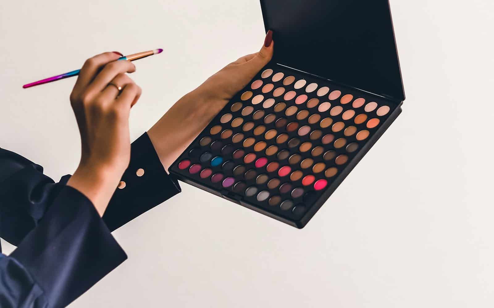 Makeup artist holding an eyeshadow palette and a brush