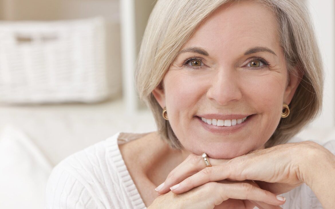 Smiling older woman with short silver hair resting her chin on her hands