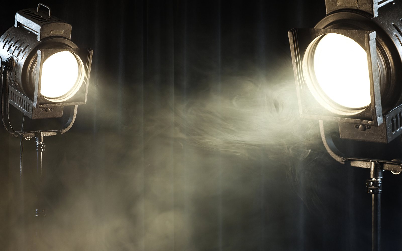 Theater spotlights shining through haze against a dark curtain