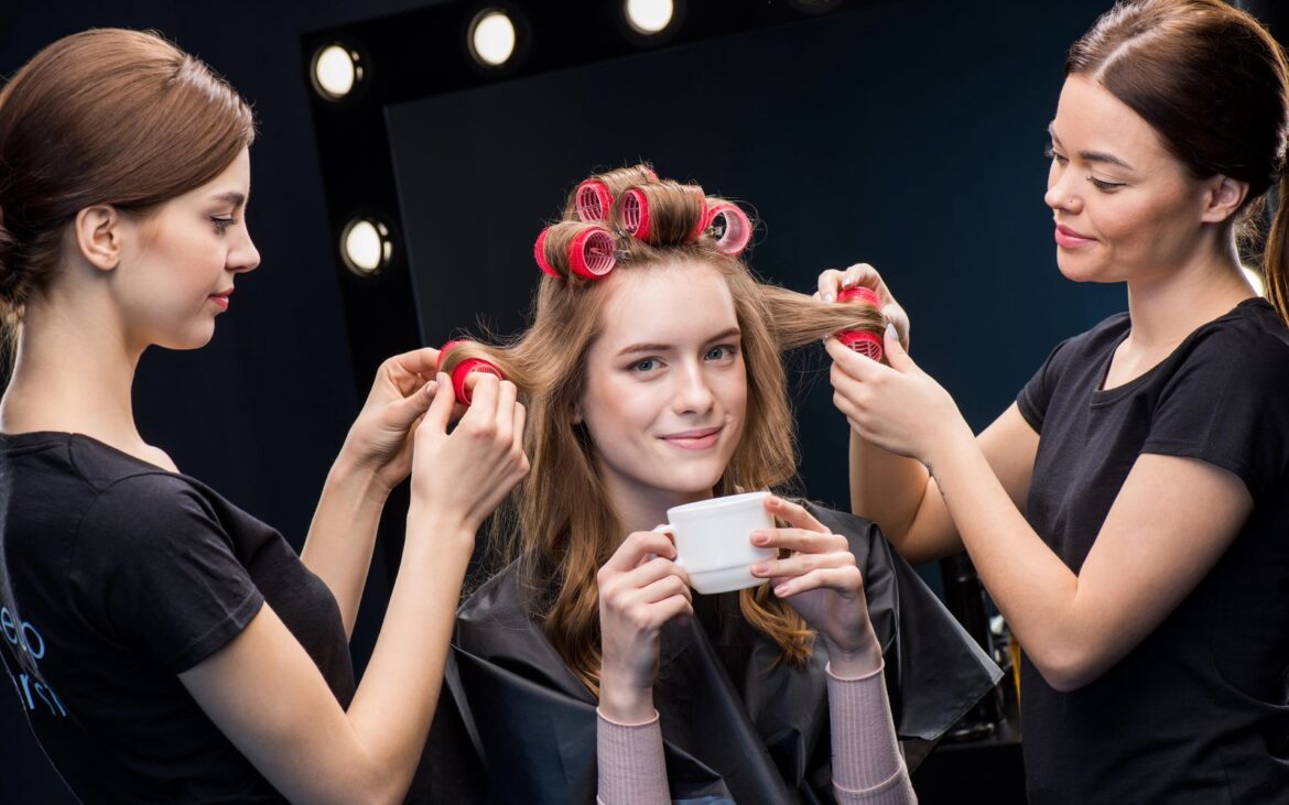 Two stylists working together on one client in a dressing room