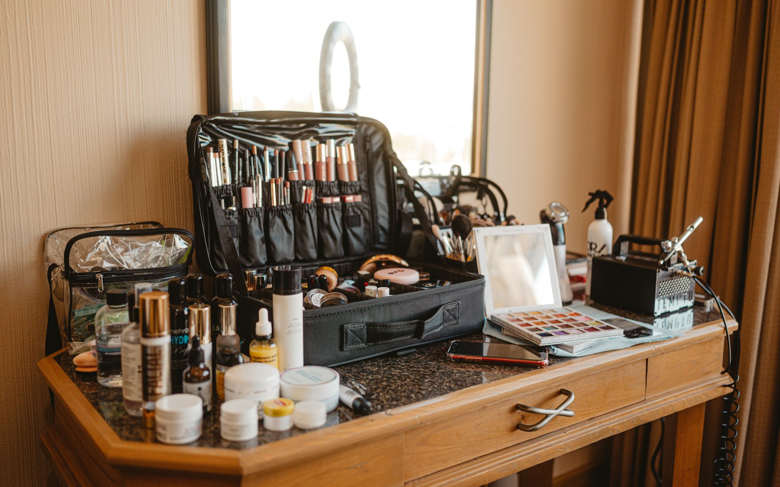 Makeup artist kit spread across a wooden vanity table