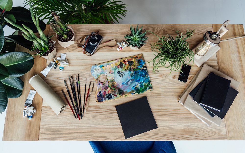 Artist desk with sketches, brushes and a watercolor palette for planning a design