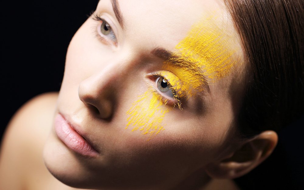 Model with soft yellow pigment brushed across her eyelid and cheek