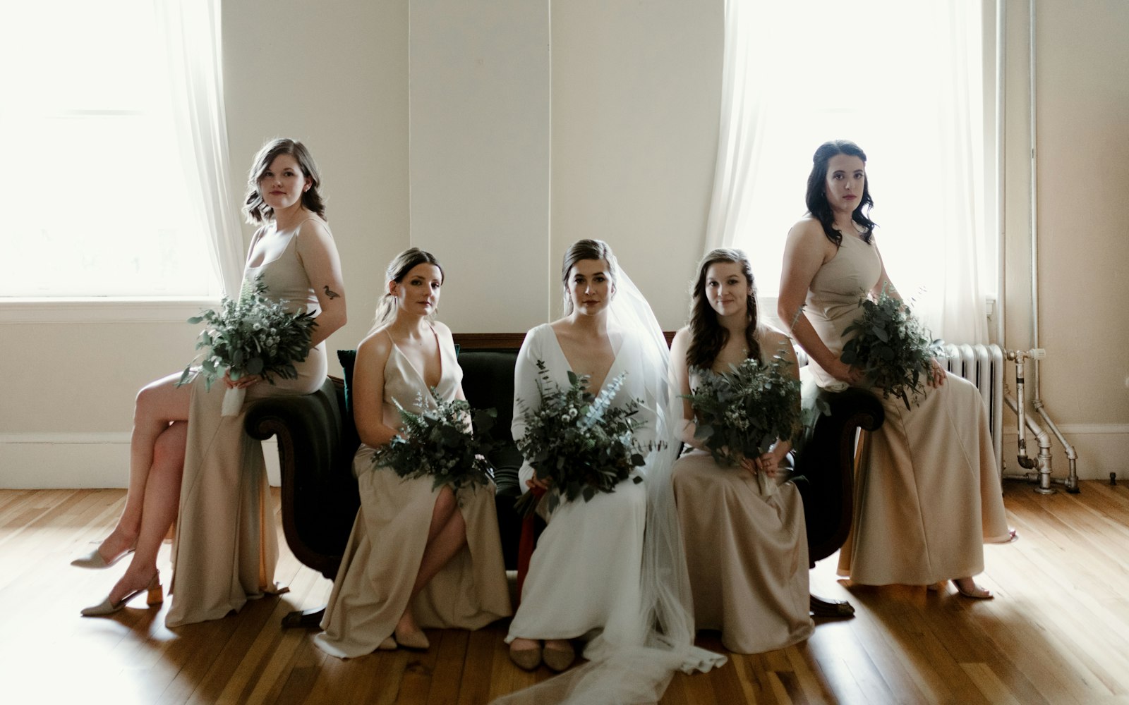 Bride and bridesmaids seated together in a sunlit room