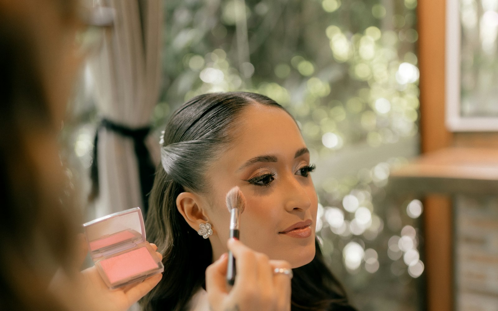 Makeup artist applying blush to a client during a bridal trial