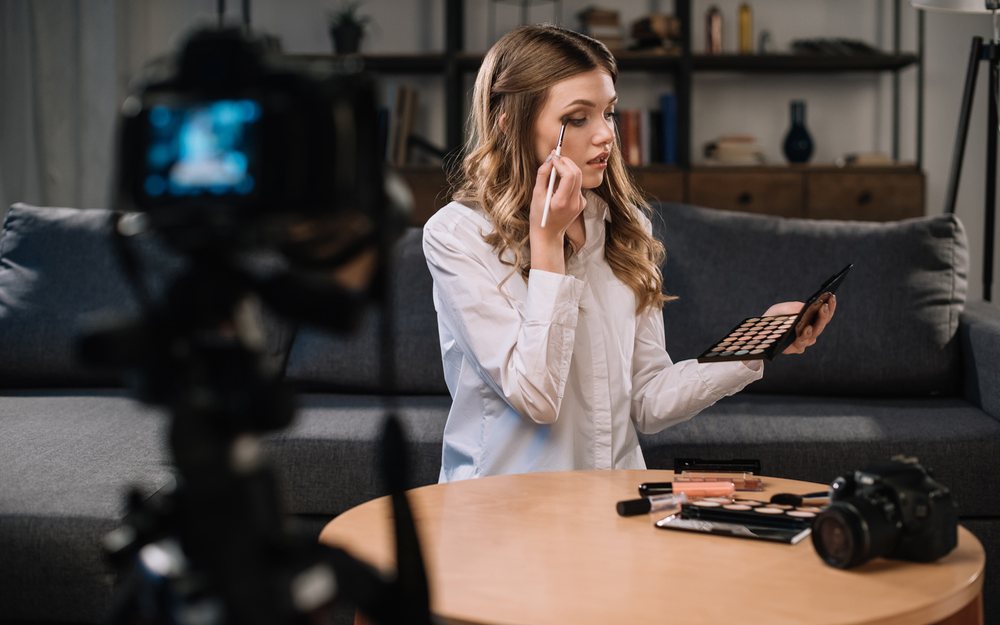 Beauty creator applying eyeshadow in front of a camera