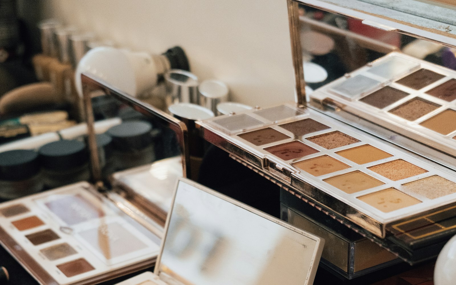 Open eyeshadow and skin-tone palettes on a makeup artist's table