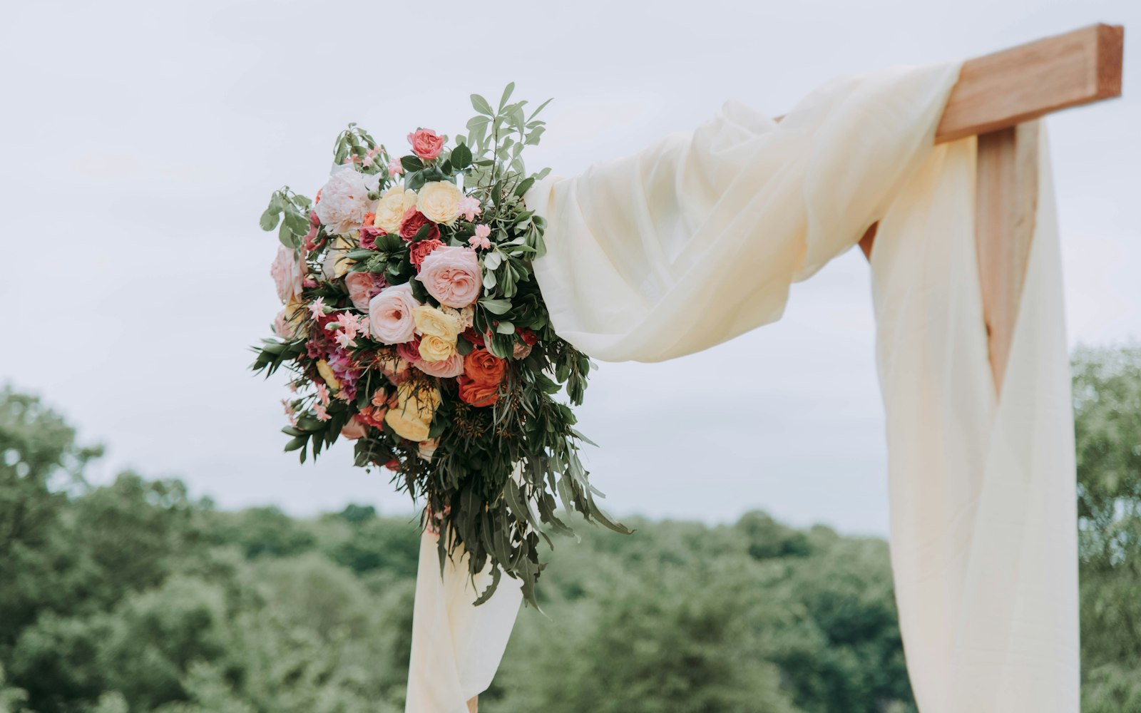 Outdoor wedding arch with flowers and draped fabric
