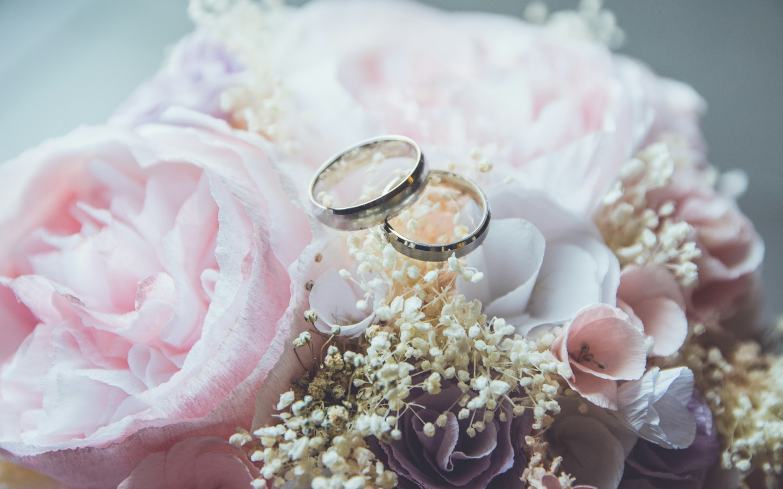Wedding rings resting on pale pink flowers