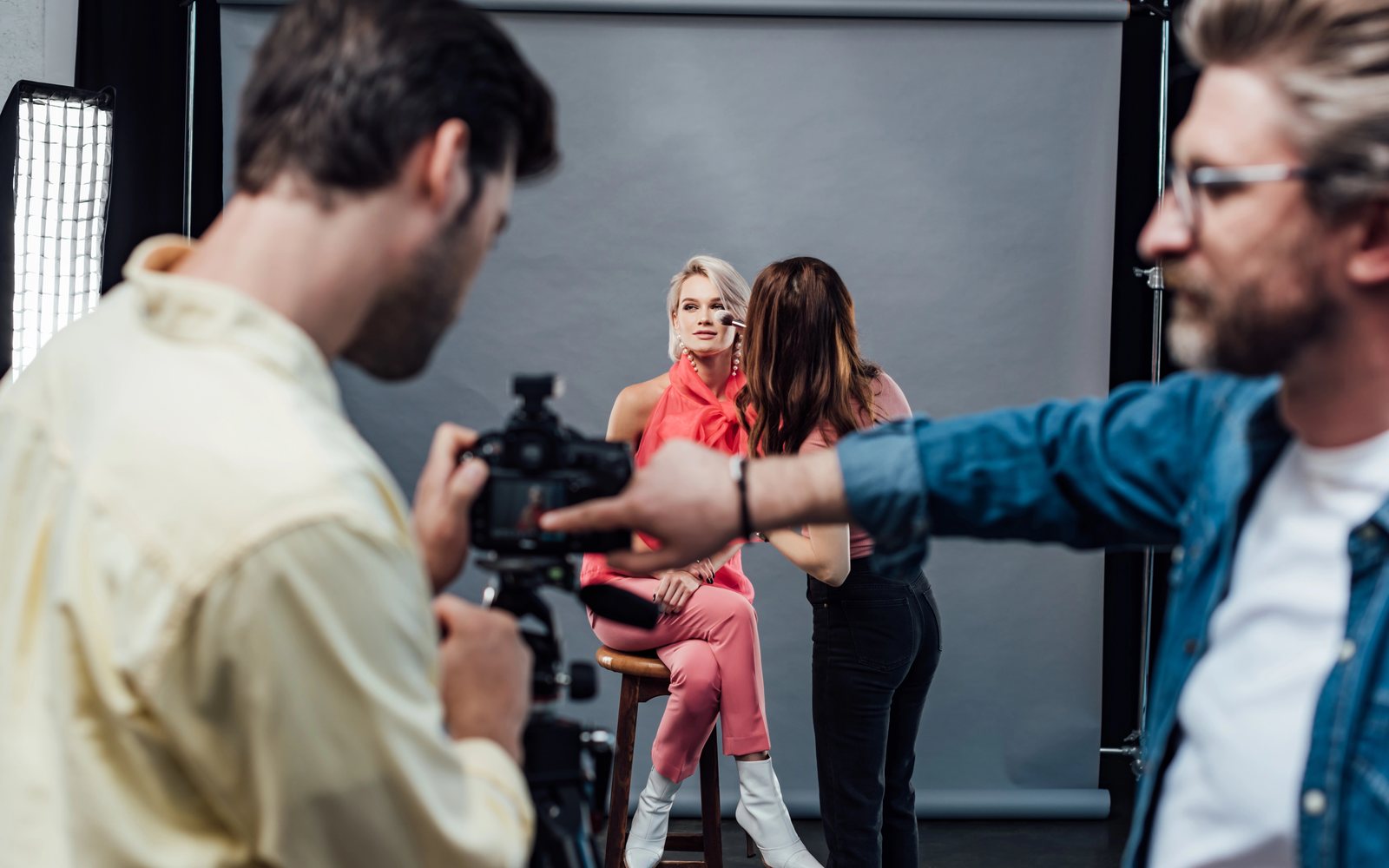 Photographer and makeup artist working with a model in a photo studio