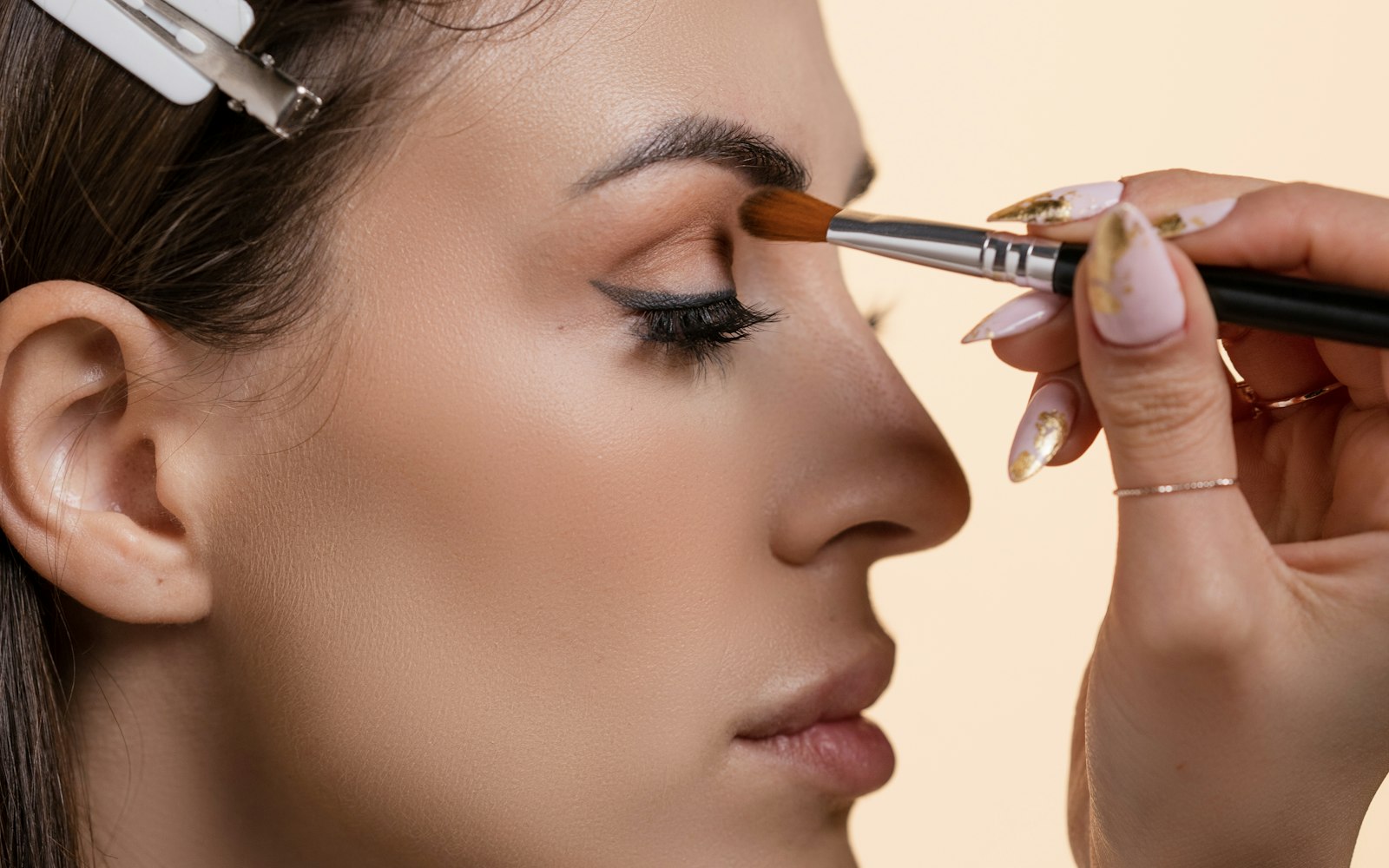 Artist applying eyeshadow to a client in profile