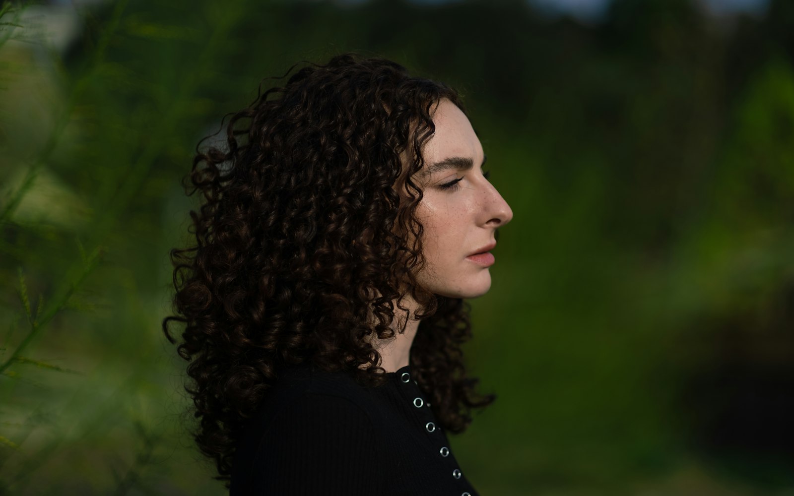 Woman with curly hair in profile outdoors