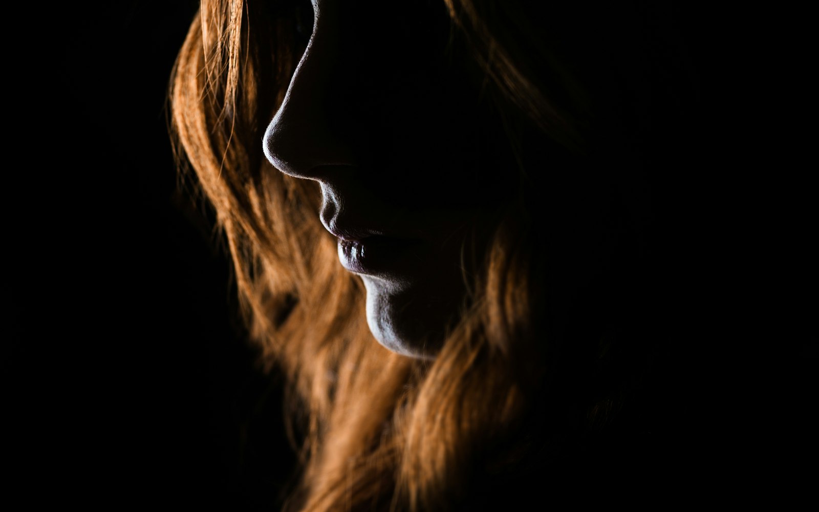 Profile lit from behind, outlining nose, lips and chin
