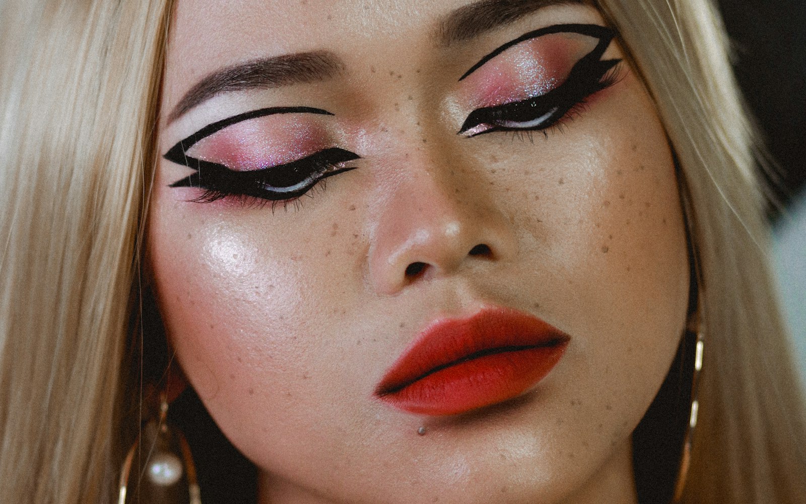 Graphic black eyeliner and red lips on freckled skin