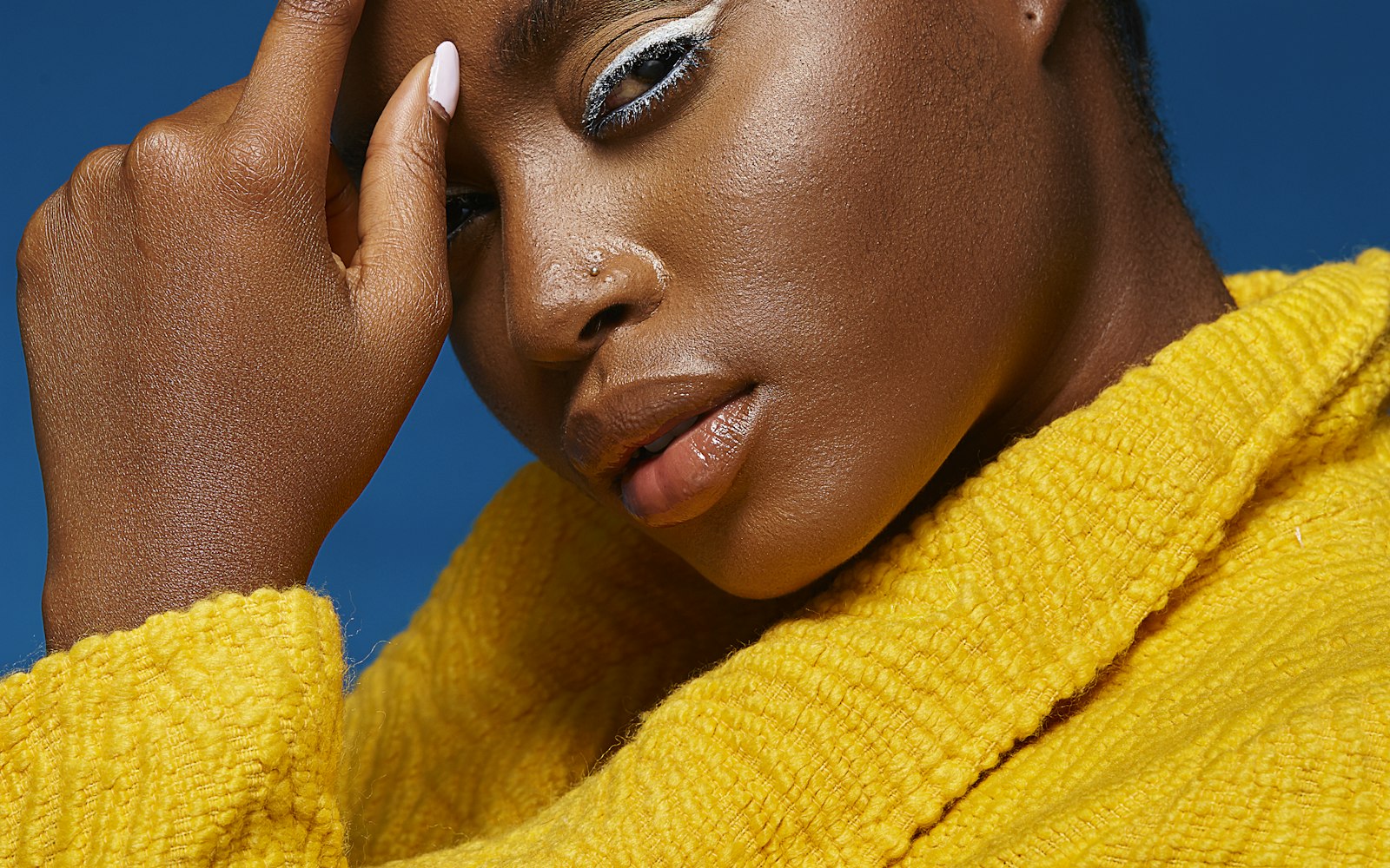 Model in a yellow sweater with white graphic eyeliner