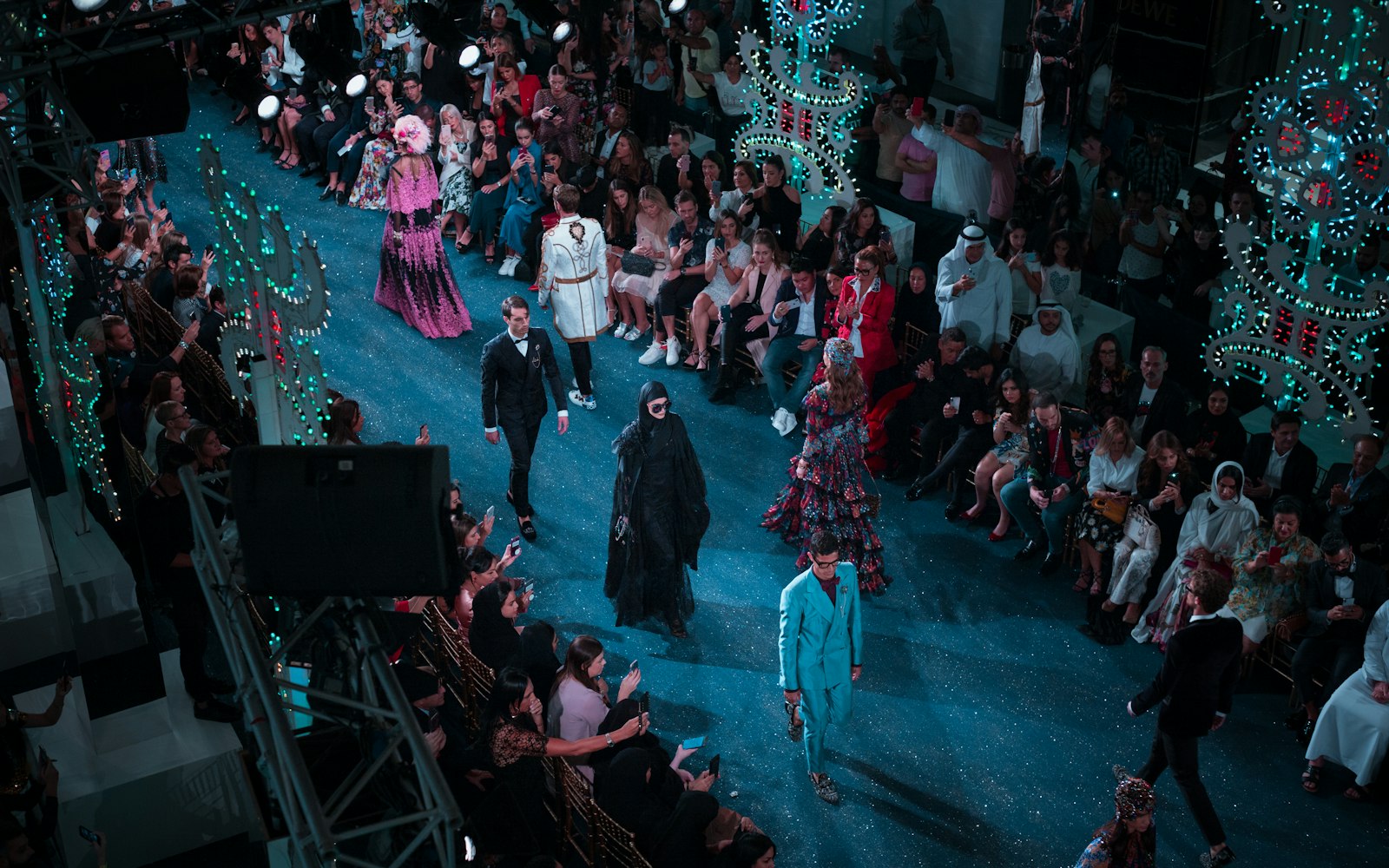 Runway show with models walking past a seated audience