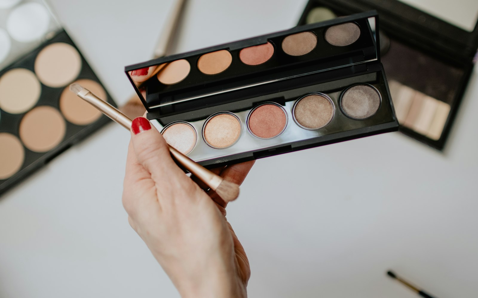 Hand holding a makeup brush over an open palette