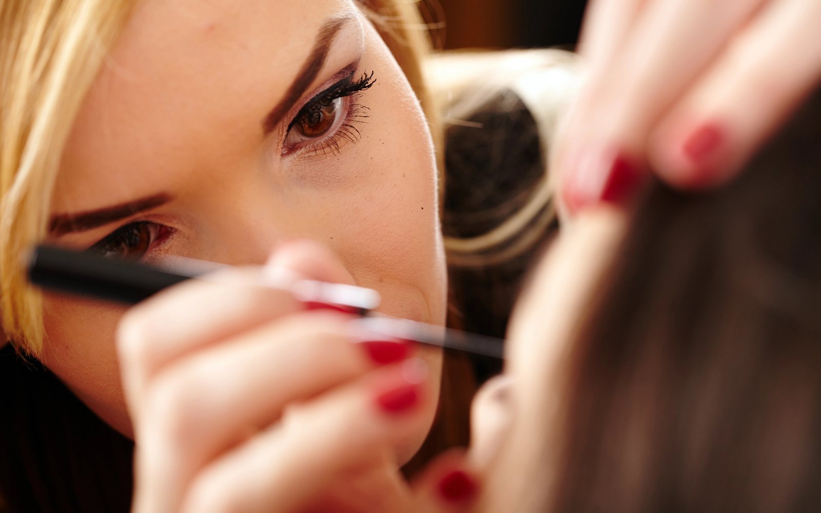 Close-up of an artist drawing eyeliner on a client
