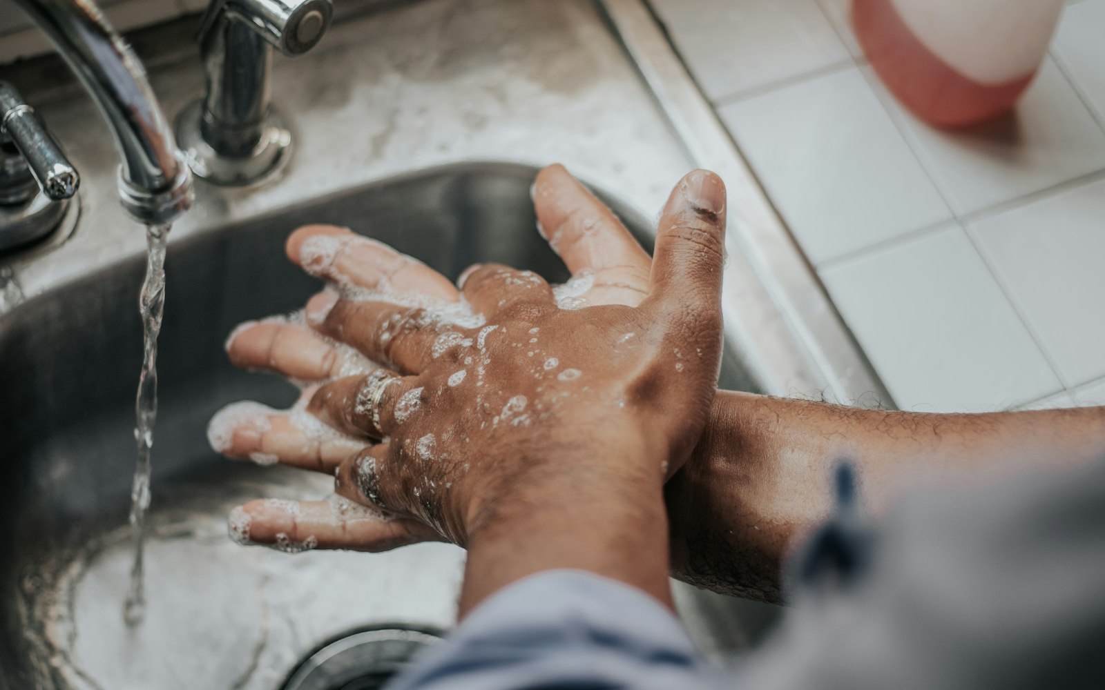 Hands being washed with soap at a sink