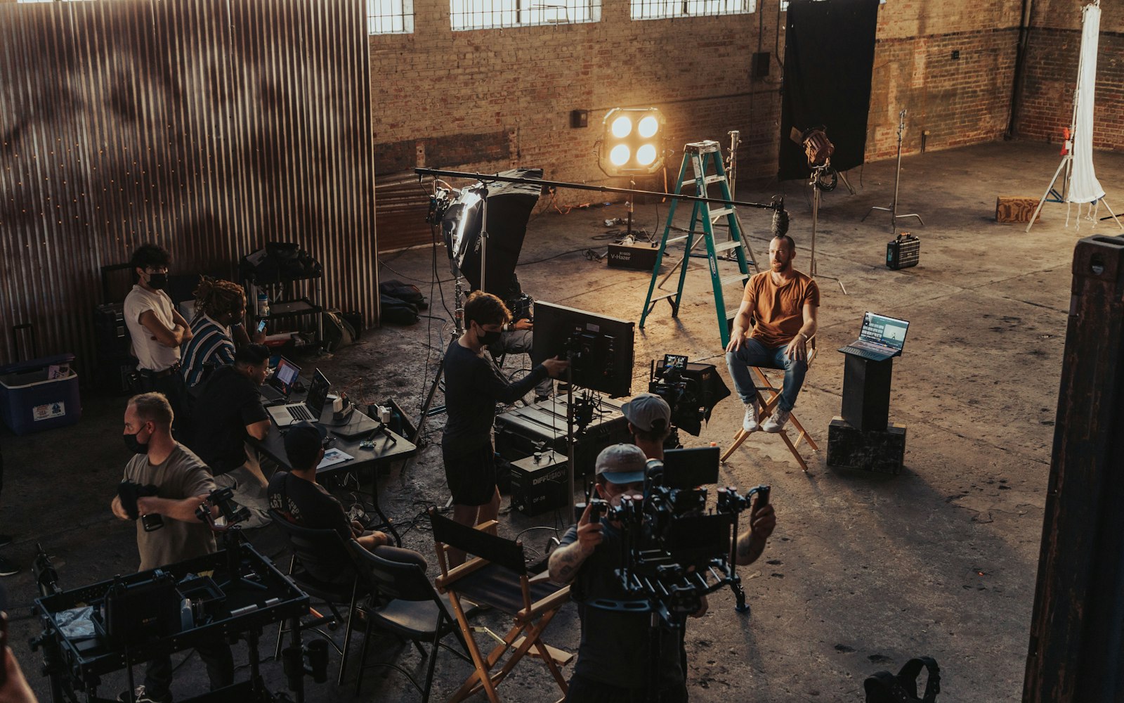 Film crew working around an actor on a warehouse set