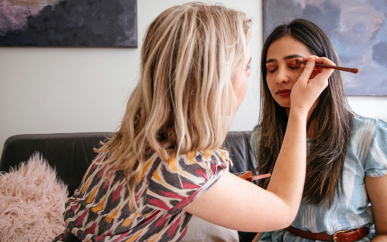 Makeup artist applying eyeshadow to a client at home