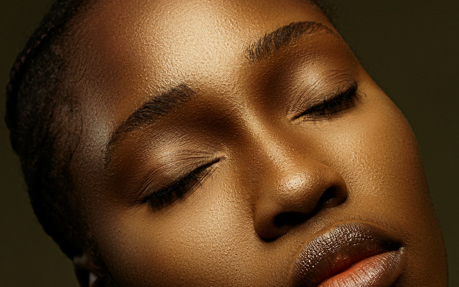 Close-up of glowing skin and closed eyes in warm light