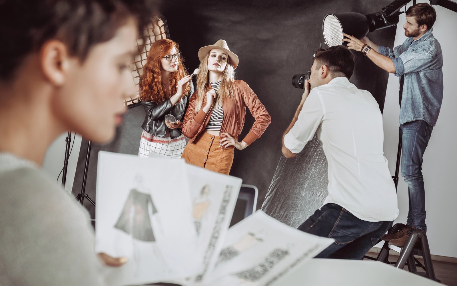 Fashion team at work during a studio shoot, with sketches in the foreground