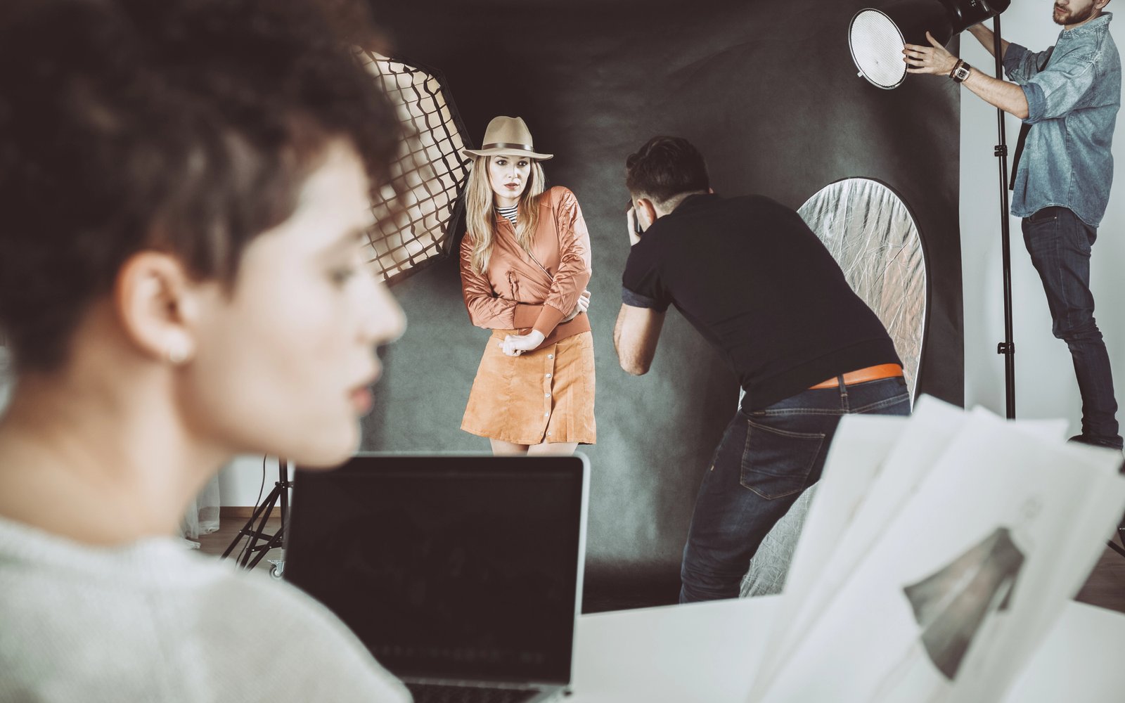 Photographer and model on set, with an artist reviewing sketches