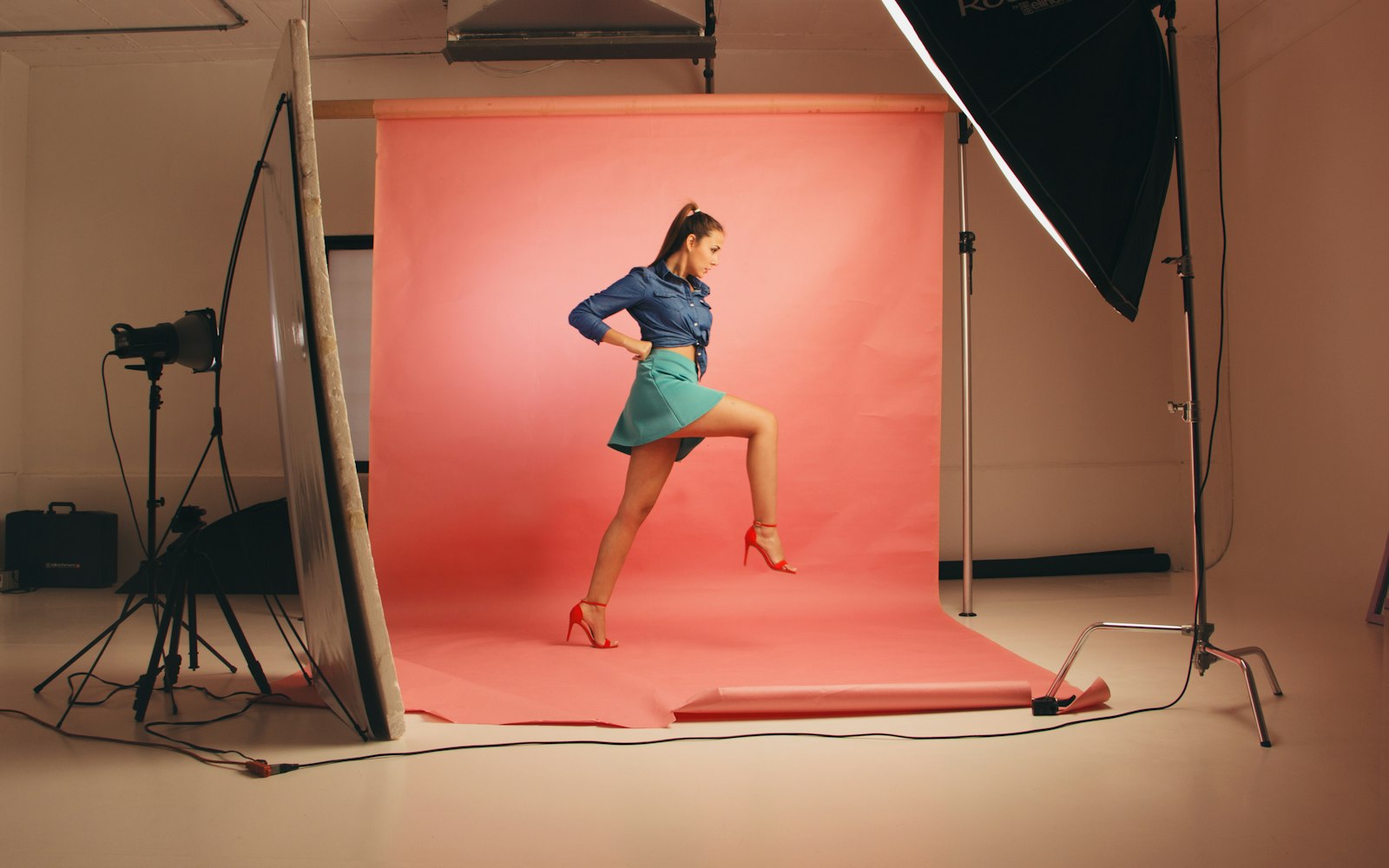 Model posing against a coral backdrop with studio lights