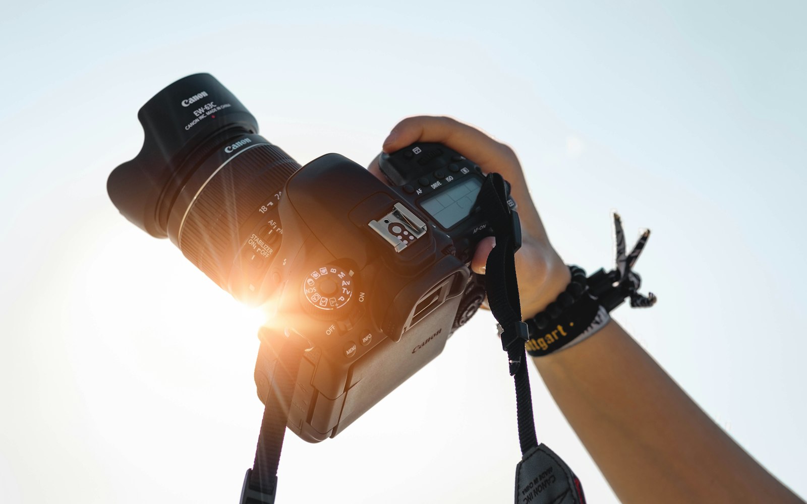 Hand holding a camera up toward bright light