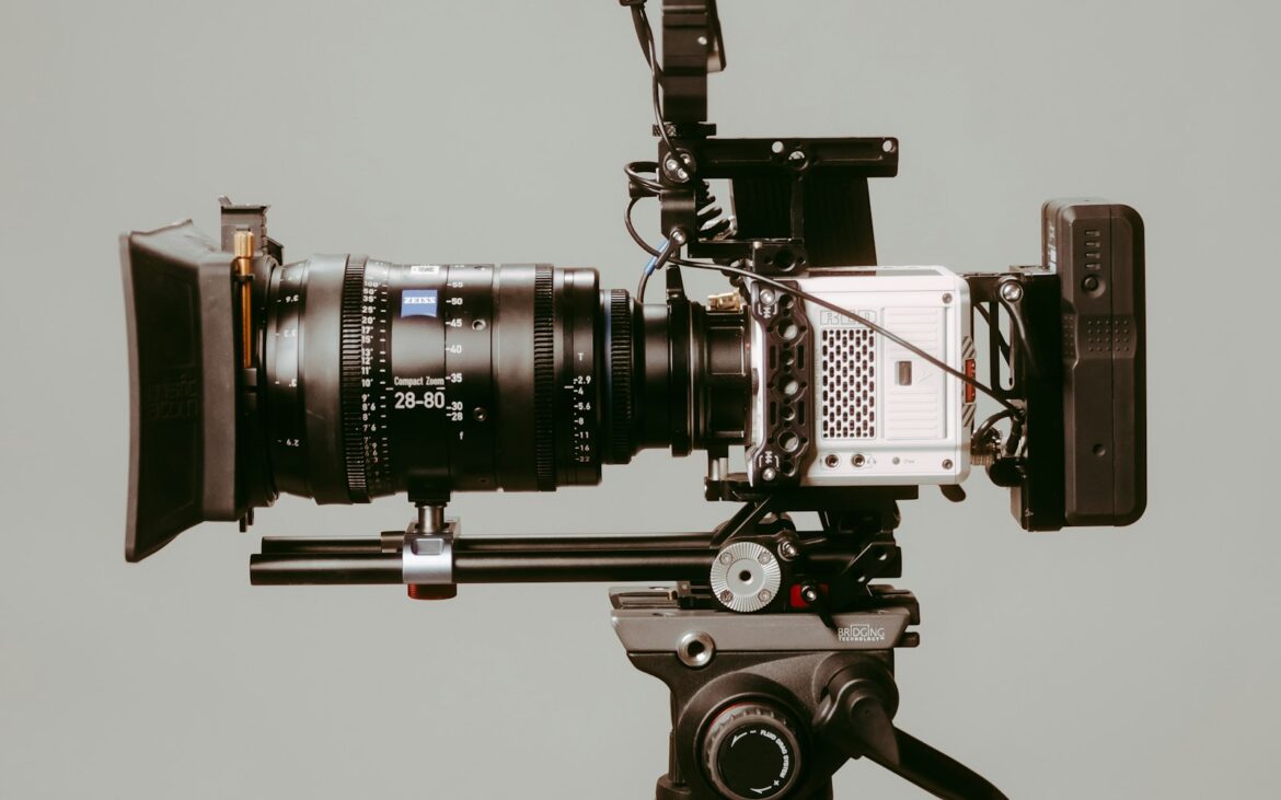 Cinema camera with a large lens on a tripod against a pale wall