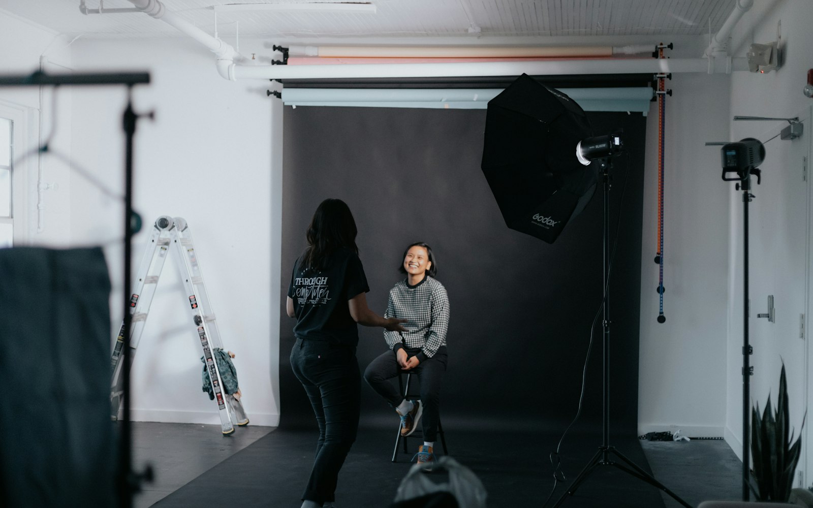 Photographer shooting a seated model in a studio with a softbox