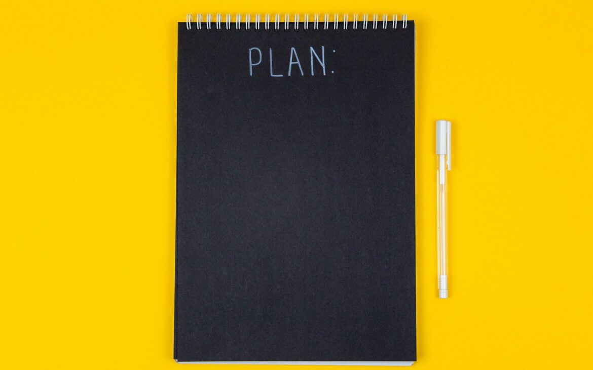 Spiral notebook with the word plan on a desk