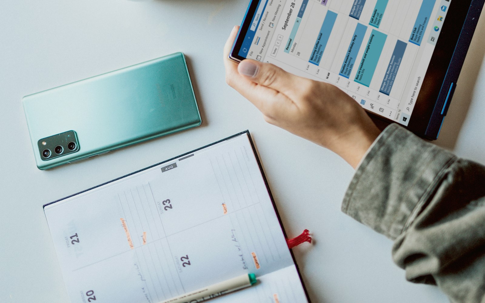 Person holding a tablet beside a coffee mug while planning