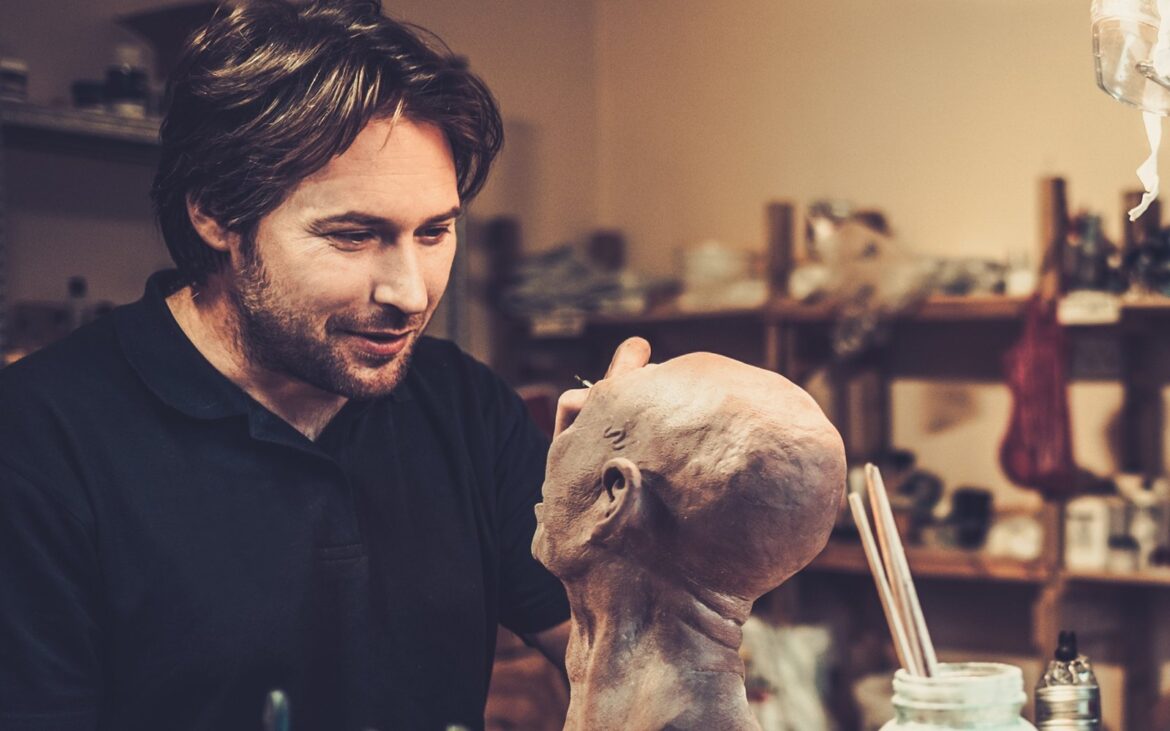 Effects artist sculpting a creature prosthetic in a workshop