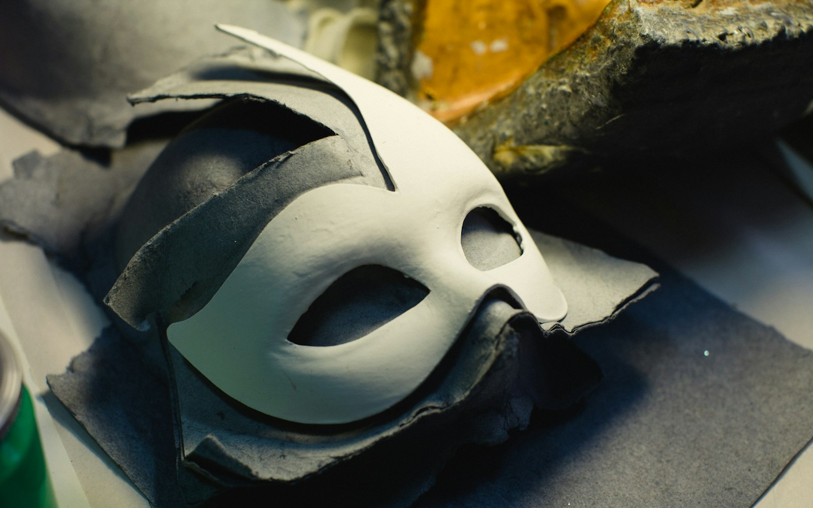 White face mask cast resting on a dark workbench