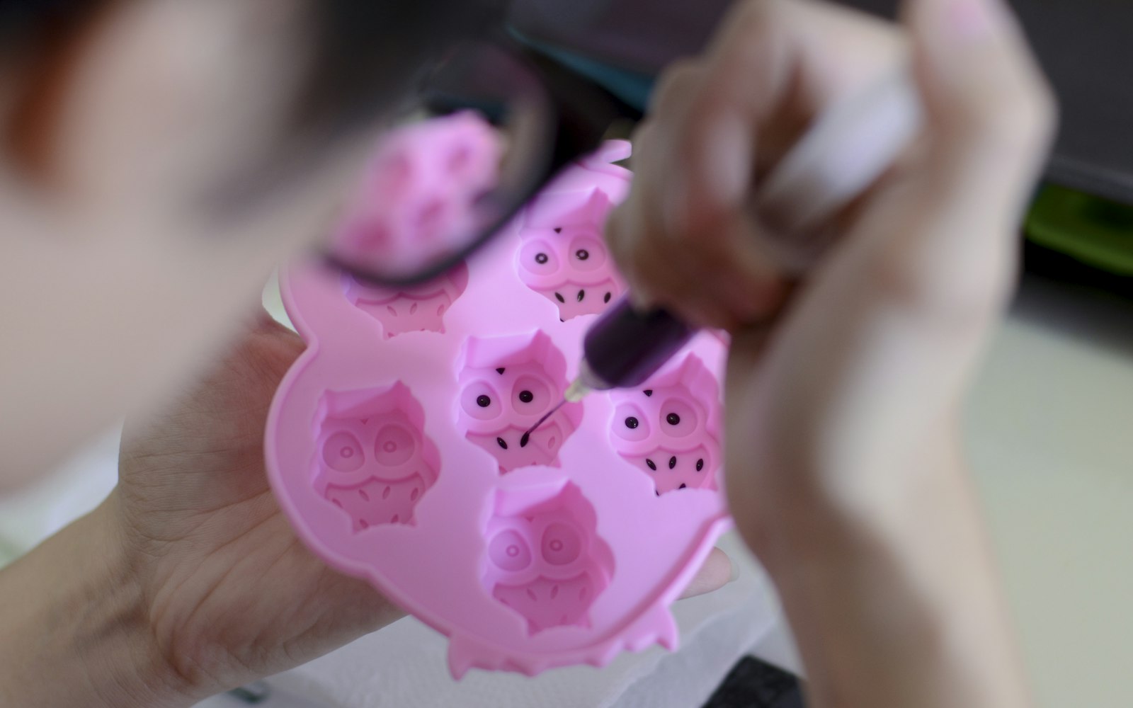 Hands detailing a pink silicone mold with a fine tool