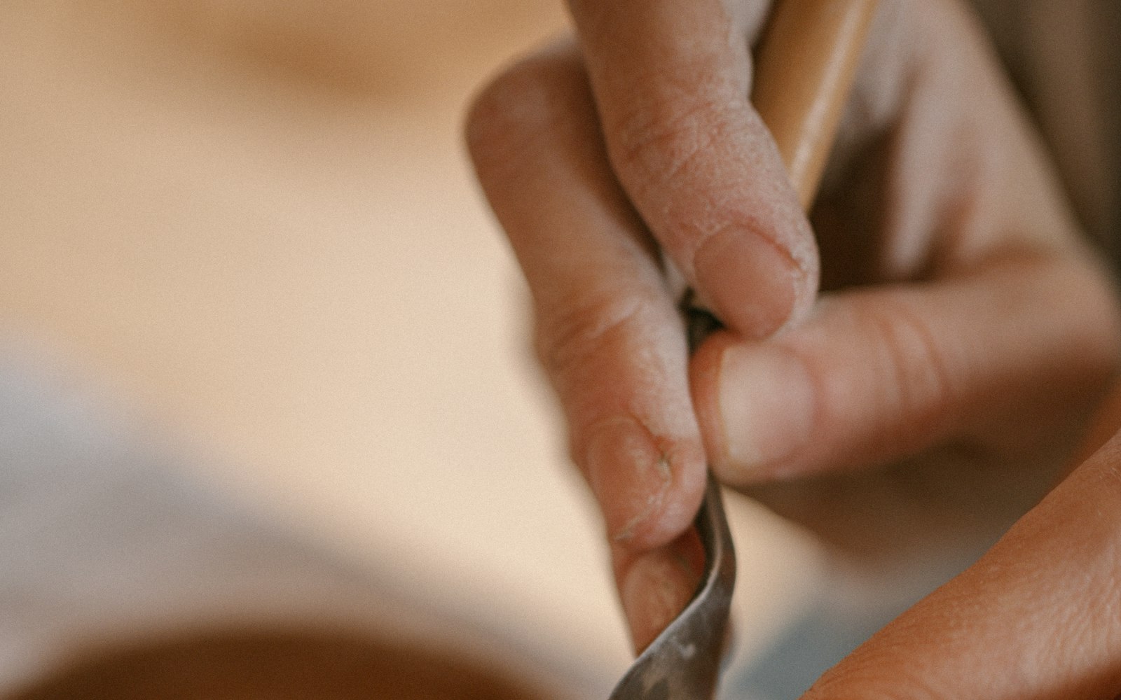 Close-up of fingers smoothing clay with a sculpting tool