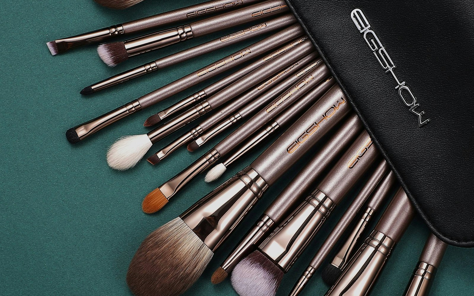Rose-gold brush set fanned beside a black brush case