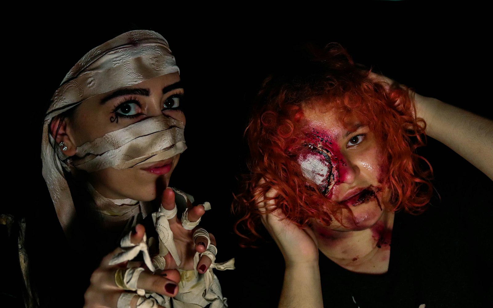 Two performers in horror makeup, one bandaged and one with a head wound