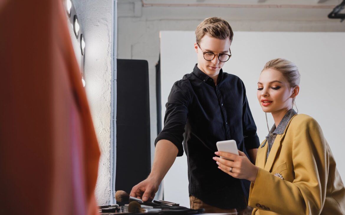 Makeup artist preparing brushes at a station beside a model backstage
